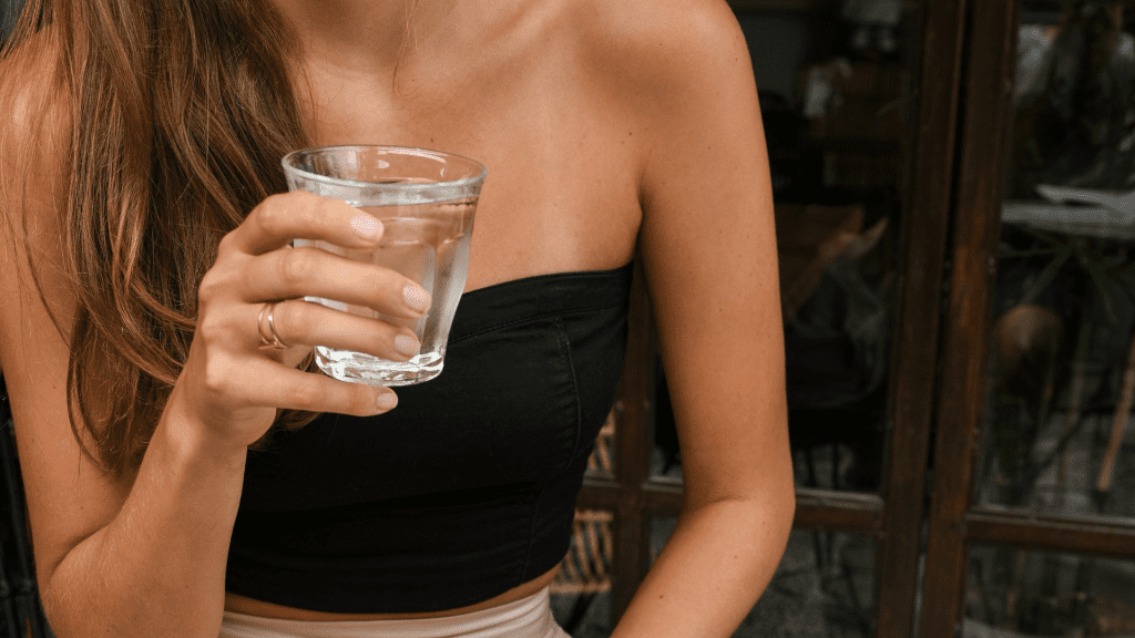 A woman holding a glass of water.