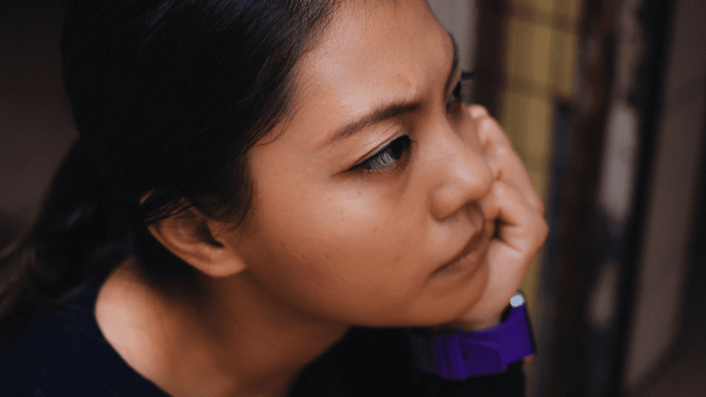 Close up image of a woman frowning from concentrating, hand resting on left hand.