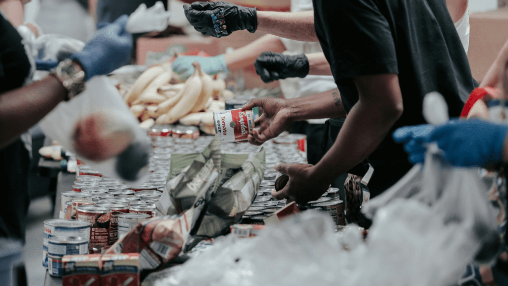 Close up of a man's hand offering soup at a food distribution center.