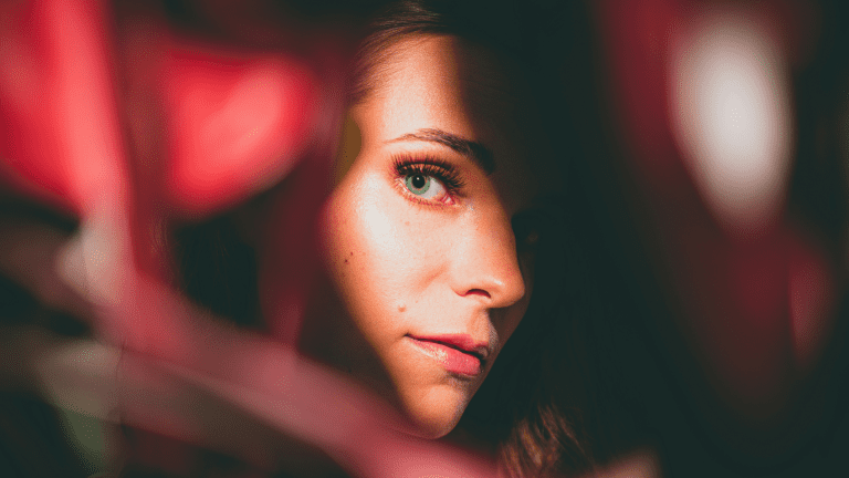 A woman looking at her reflection in a sliver of a mirror.